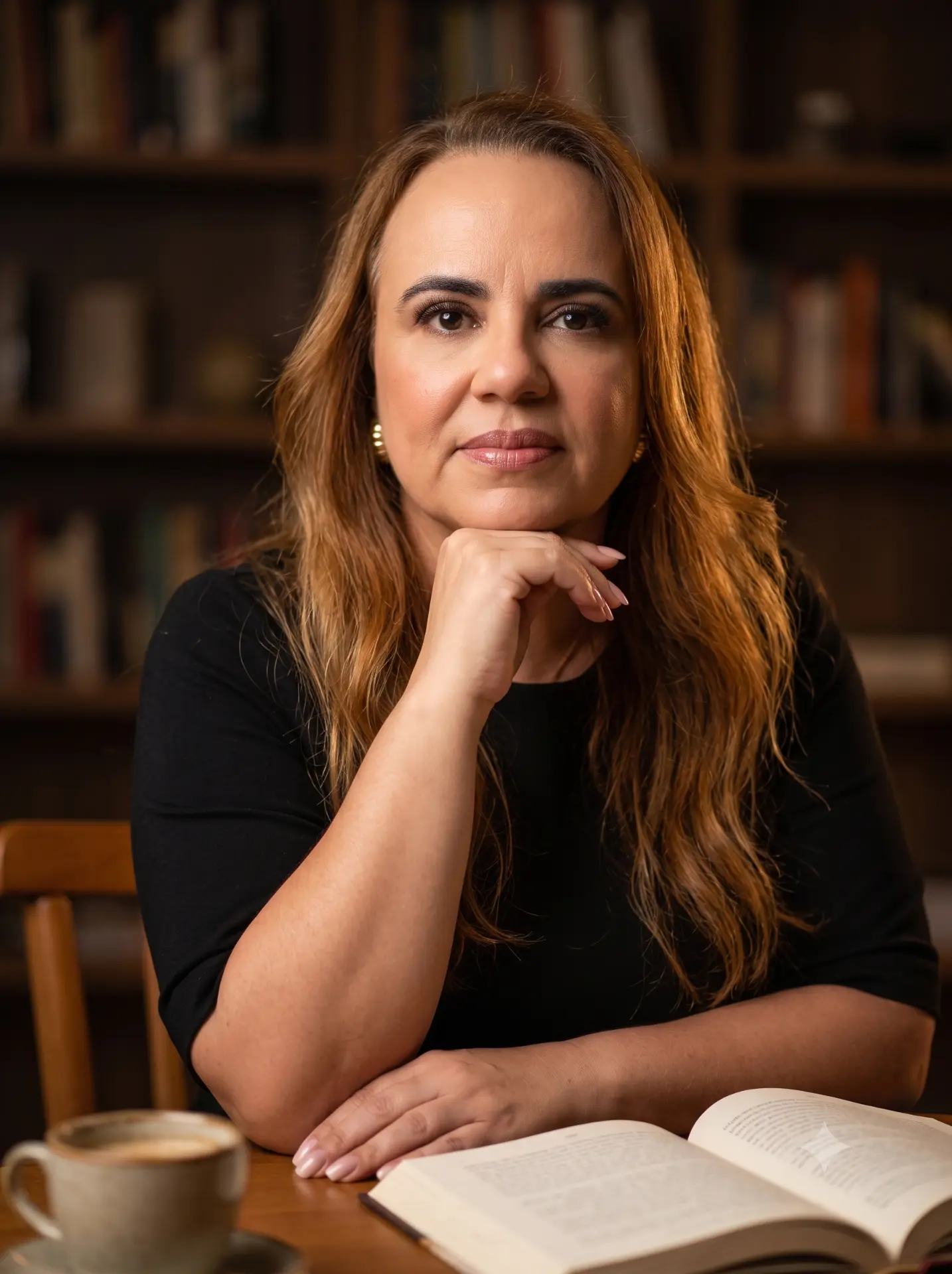 Cíntia Leão, autora do livro O Buquê, sentada em uma biblioteca